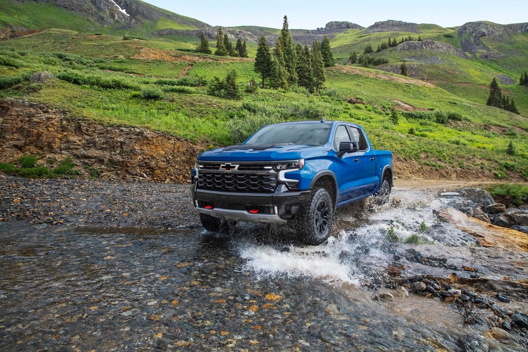 blue chevy truck offroading through a stream